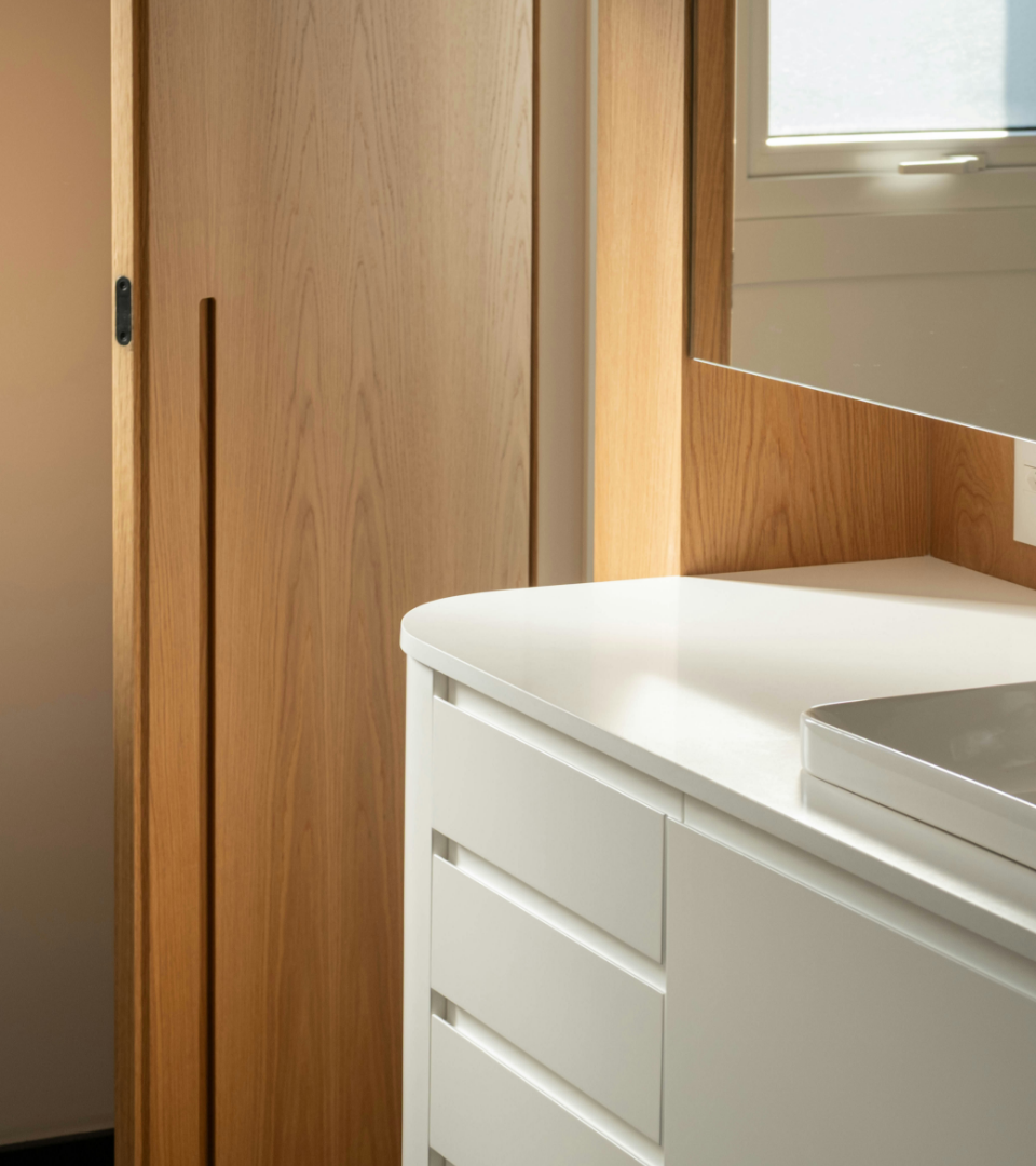 A modern bathroom detail showing a white vanity with drawers and a light wood sliding door.